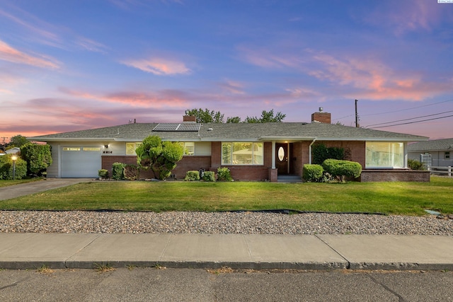 2214 W Clearwater Ave, Kennewick, WA 99336 - ranch-style home featuring an attached garage, concrete driveway, roof mounted solar panels, a chimney, and a lawn