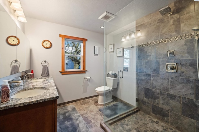 bathroom featuring a sink, toilet, a stall shower, and double vanity