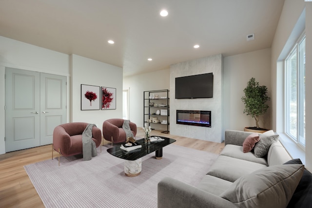 living room featuring a large fireplace and light hardwood / wood-style floors