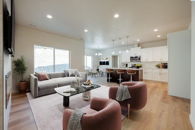 living room featuring an inviting chandelier, a fireplace, and light hardwood / wood-style flooring