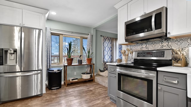 kitchen with dark wood finished floors, light countertops, backsplash, appliances with stainless steel finishes, and white cabinets