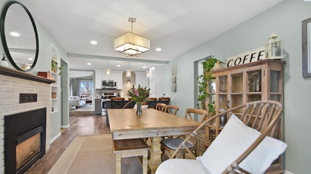 dining room with dark wood-style floors, a fireplace, and recessed lighting