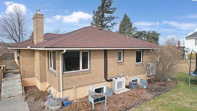 back of house featuring a trampoline, brick siding, and a chimney