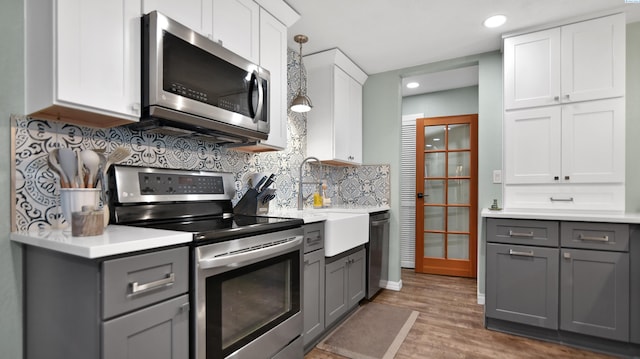 kitchen featuring stainless steel appliances, light countertops, and gray cabinetry