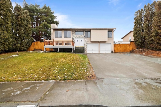 view of front of house featuring an attached garage, a front yard, fence, stone siding, and driveway