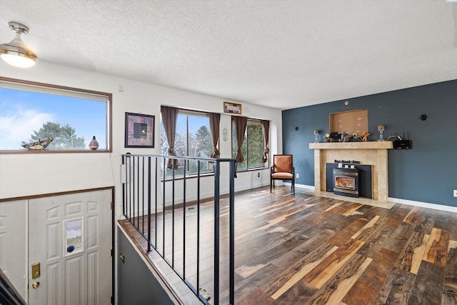 living area featuring a textured ceiling, baseboards, dark wood-style flooring, and a tiled fireplace