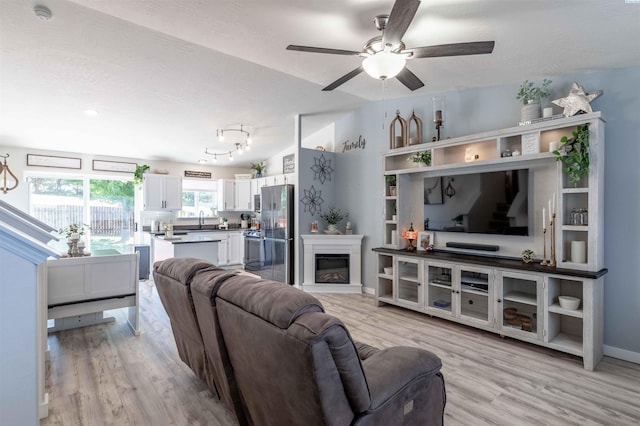 living room featuring lofted ceiling, sink, ceiling fan, a textured ceiling, and light hardwood / wood-style flooring