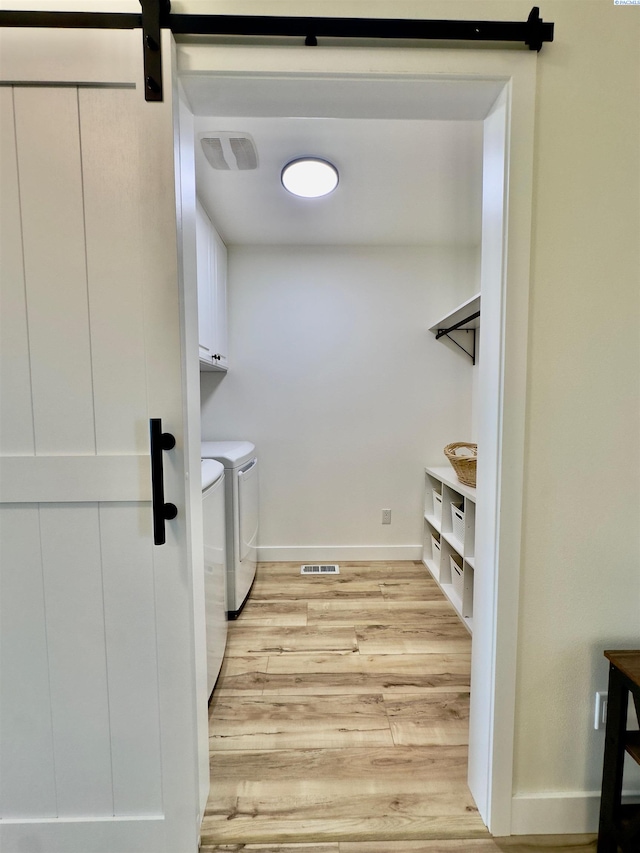 4516 NW Commons Dr, Pasco, WA 99301 - laundry room with cabinet space, separate washer and dryer, light wood-type flooring, and a barn door