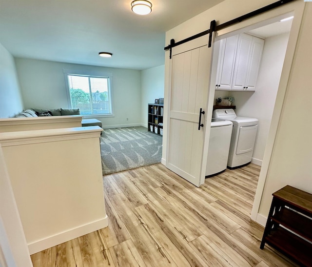 4516 NW Commons Dr, Pasco, WA 99301 - washroom featuring cabinet space, washer and dryer, a barn door, and light wood-style flooring