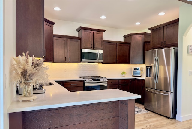 4516 NW Commons Dr, Pasco, WA 99301 - kitchen with stainless steel appliances, dark brown cabinets, a peninsula, light countertops, and tasteful backsplash