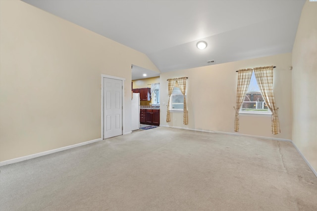 carpeted empty room featuring vaulted ceiling and a wealth of natural light