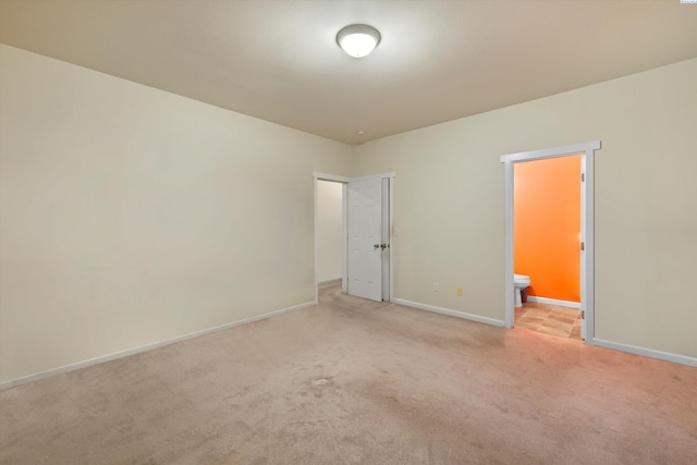 unfurnished bedroom featuring light colored carpet and ensuite bathroom