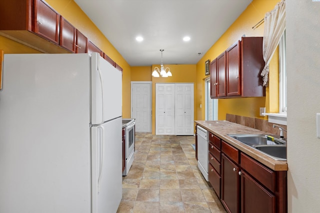 kitchen featuring sink, a notable chandelier, white appliances, and decorative light fixtures