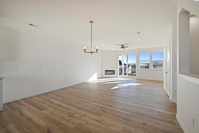 125 Claret Dr, Prosser, WA 99350 - unfurnished living room with light wood-type flooring, ceiling fan with notable chandelier, baseboards, visible vents, and a glass covered fireplace
