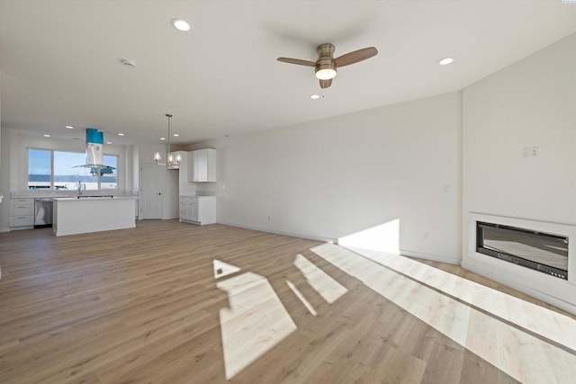 125 Claret Dr, Prosser, WA 99350 - unfurnished living room with a sink, a glass covered fireplace, light wood-type flooring, ceiling fan with notable chandelier, and recessed lighting