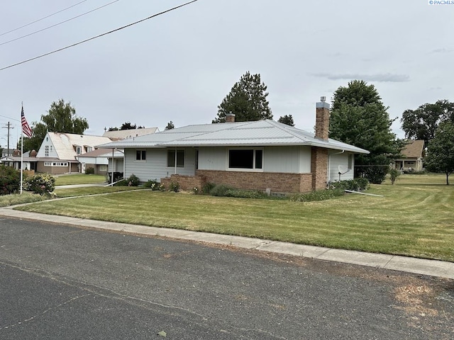 404 D St, Endicott, WA 99125 - view of front of property with a chimney, a front yard, brick siding, and a metal roof
