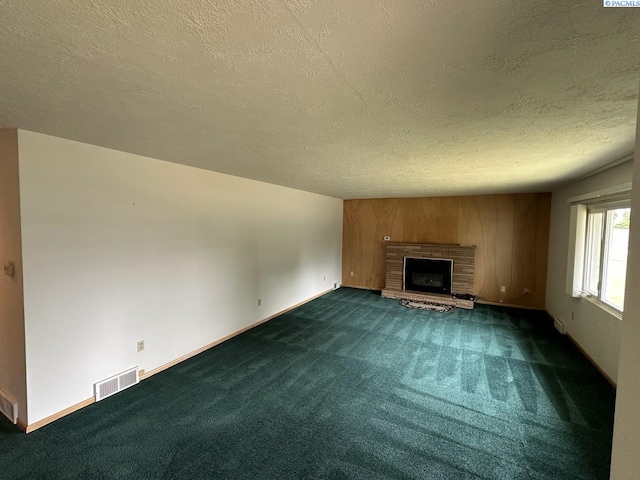 404 D St, Endicott, WA 99125 - unfurnished living room with a textured ceiling, dark carpet, and a fireplace with raised hearth