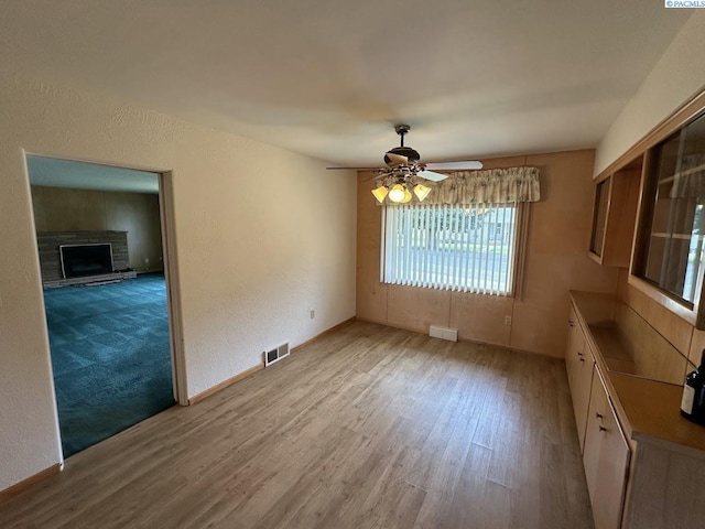 404 D St, Endicott, WA 99125 - unfurnished dining area with wood finished floors, a ceiling fan, a fireplace with raised hearth, and a textured wall