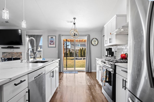 kitchen with white cabinetry, stainless steel appliances, sink, and hanging light fixtures