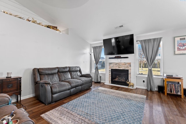 living room with lofted ceiling, a stone fireplace, and dark hardwood / wood-style flooring