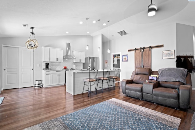 living room featuring dark hardwood / wood-style floors, ceiling fan, a barn door, and high vaulted ceiling