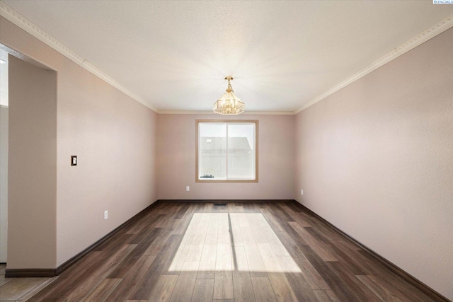 empty room with a notable chandelier, baseboards, dark wood finished floors, and crown molding