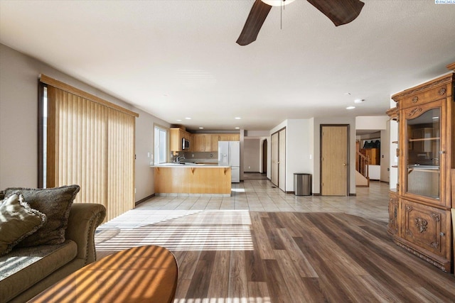 unfurnished living room featuring ceiling fan, recessed lighting, baseboards, and light wood-style floors