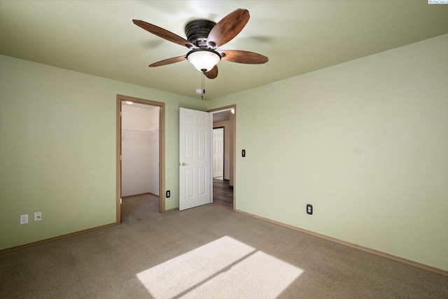 unfurnished bedroom featuring ceiling fan, light carpet, baseboards, a closet, and a walk in closet