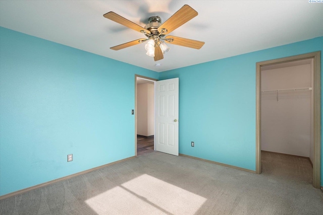 unfurnished bedroom featuring baseboards, ceiling fan, a walk in closet, carpet flooring, and a closet