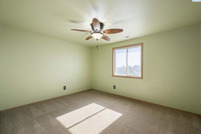 spare room featuring a ceiling fan, visible vents, light carpet, and baseboards