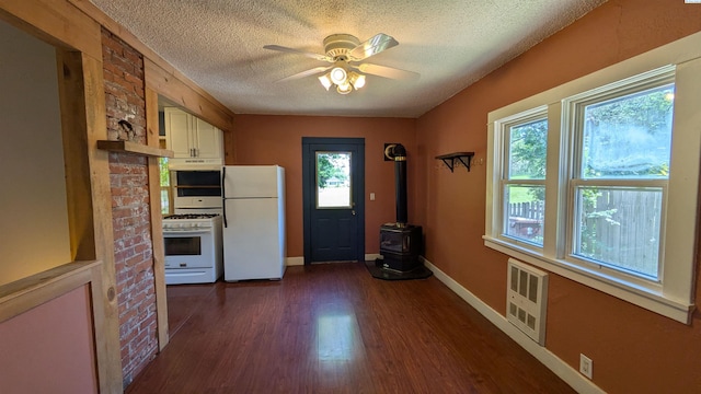 535 SE Side St, Pullman, WA 99163 - kitchen with white appliances, a wood stove, a textured ceiling, plenty of natural light, and white cabinets