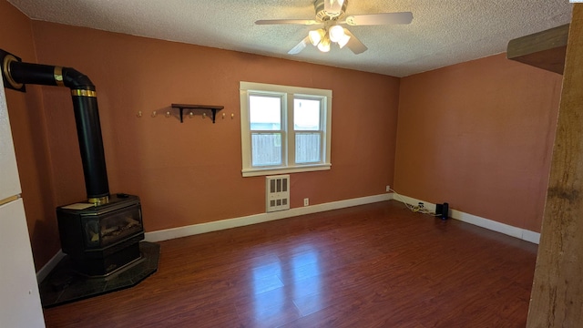 535 SE Side St, Pullman, WA 99163 - empty room with a wood stove, a textured ceiling, heating unit, wood finished floors, and a ceiling fan