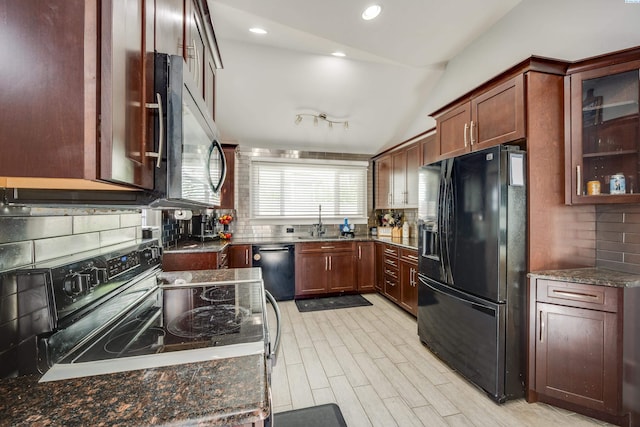 kitchen featuring black appliances, dark stone countertops, a sink, and glass insert cabinets