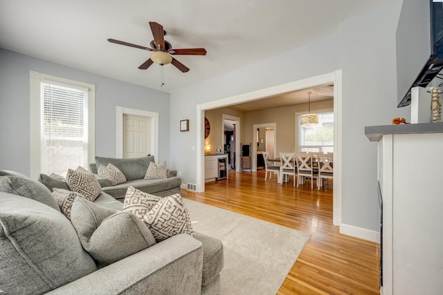 living room featuring ceiling fan, wood finished floors, and baseboards