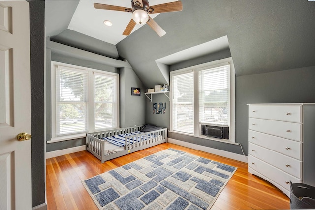 bedroom featuring a ceiling fan, lofted ceiling, light wood-style flooring, and baseboards