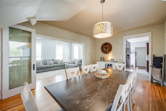 dining room with light wood-type flooring and vaulted ceiling