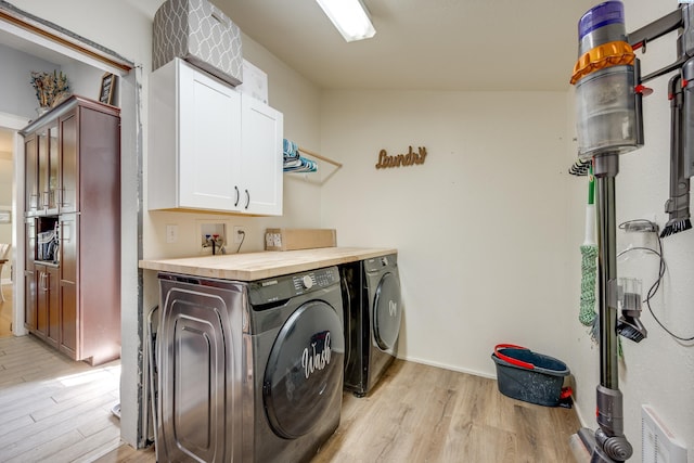 laundry room with cabinet space, visible vents, light wood-style floors, and washer and dryer