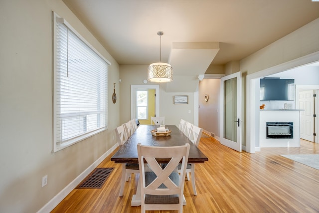 dining area with baseboards, a fireplace, visible vents, and wood finished floors