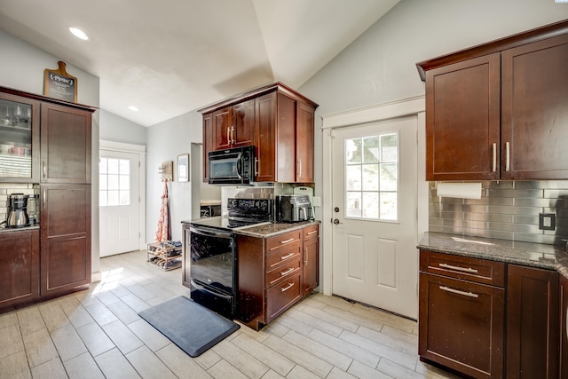 kitchen featuring glass insert cabinets, dark stone countertops, vaulted ceiling, black appliances, and backsplash