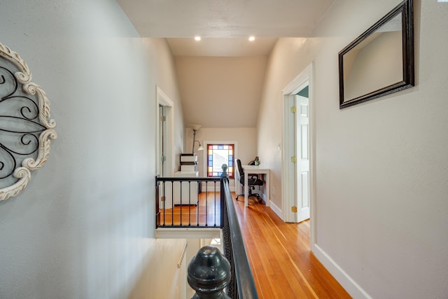 hall featuring wood finished floors, an upstairs landing, and baseboards