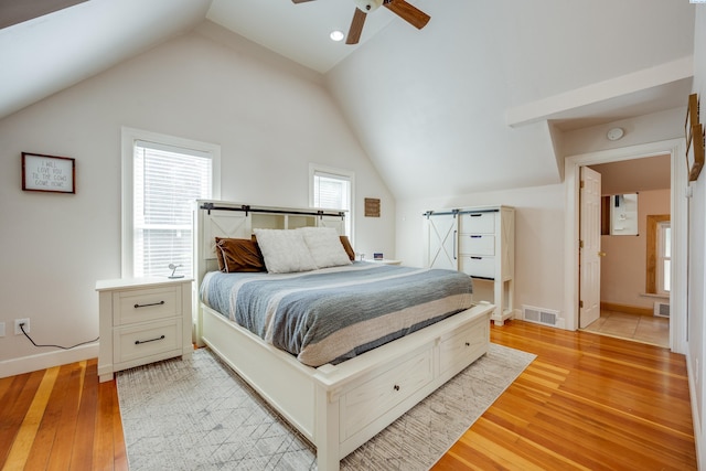 bedroom featuring baseboards, visible vents, a ceiling fan, vaulted ceiling, and light wood-type flooring