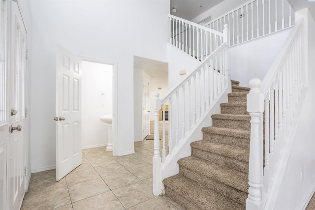 stairway with tile patterned floors and a high ceiling