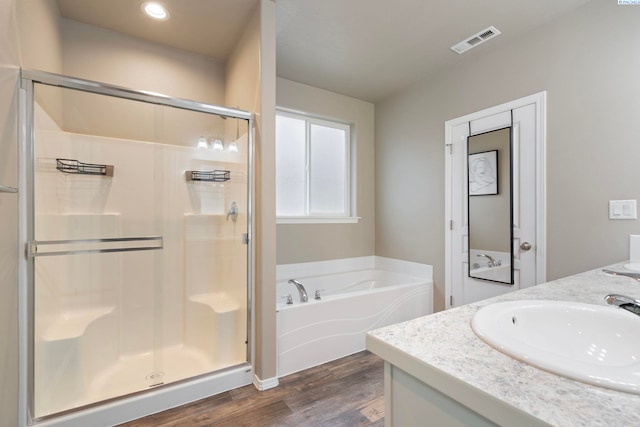 bathroom with hardwood / wood-style flooring, vanity, and plus walk in shower