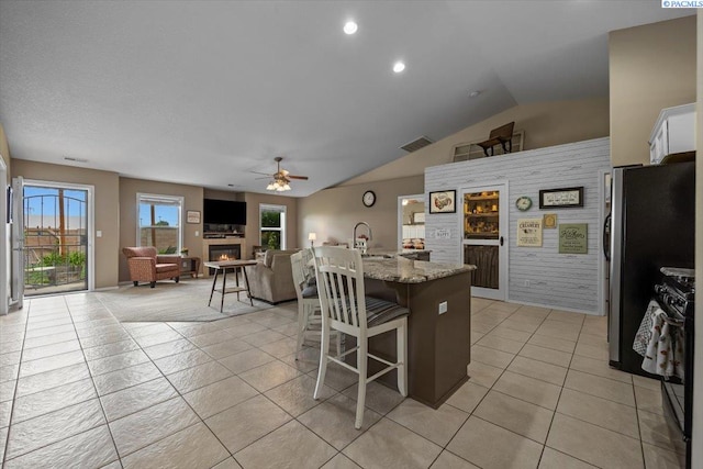 8602 W 1st Ave, Kennewick, WA 99336 - kitchen featuring a glass covered fireplace, a kitchen breakfast bar, a ceiling fan, plenty of natural light, and lofted ceiling