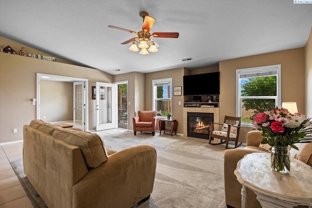 8602 W 1st Ave, Kennewick, WA 99336 - living area with plenty of natural light, a tiled fireplace, ceiling fan, a textured ceiling, and vaulted ceiling