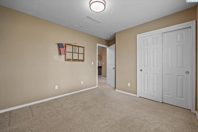 8602 W 1st Ave, Kennewick, WA 99336 - unfurnished bedroom with light colored carpet, baseboards, a textured ceiling, a closet, and attic access