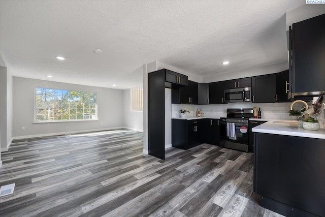 kitchen featuring appliances with stainless steel finishes, tasteful backsplash, sink, hardwood / wood-style flooring, and a textured ceiling