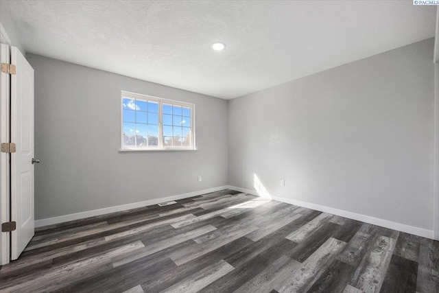 empty room featuring dark hardwood / wood-style floors and a textured ceiling