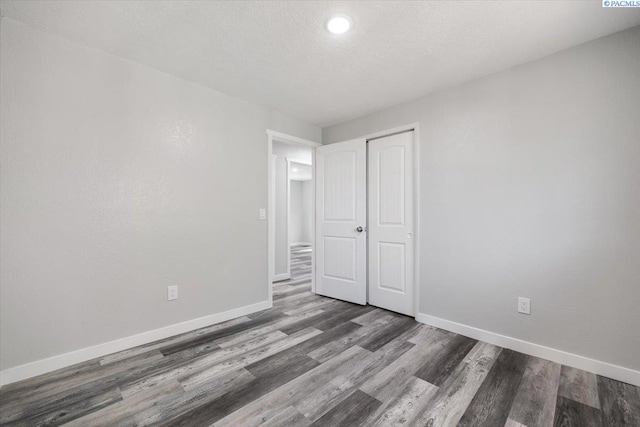 unfurnished bedroom with hardwood / wood-style flooring, a closet, and a textured ceiling