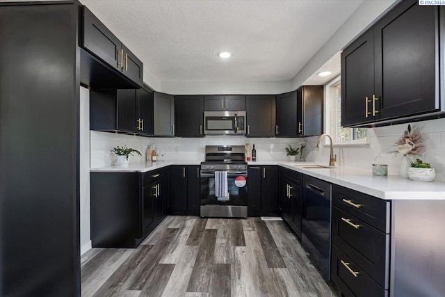 kitchen featuring appliances with stainless steel finishes, sink, wood-type flooring, and backsplash